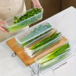 Four clear rectangular reusable plastic food storage containers arranged for refrigerator organization
