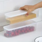 Four clear rectangular reusable plastic food storage containers arranged for refrigerator organization